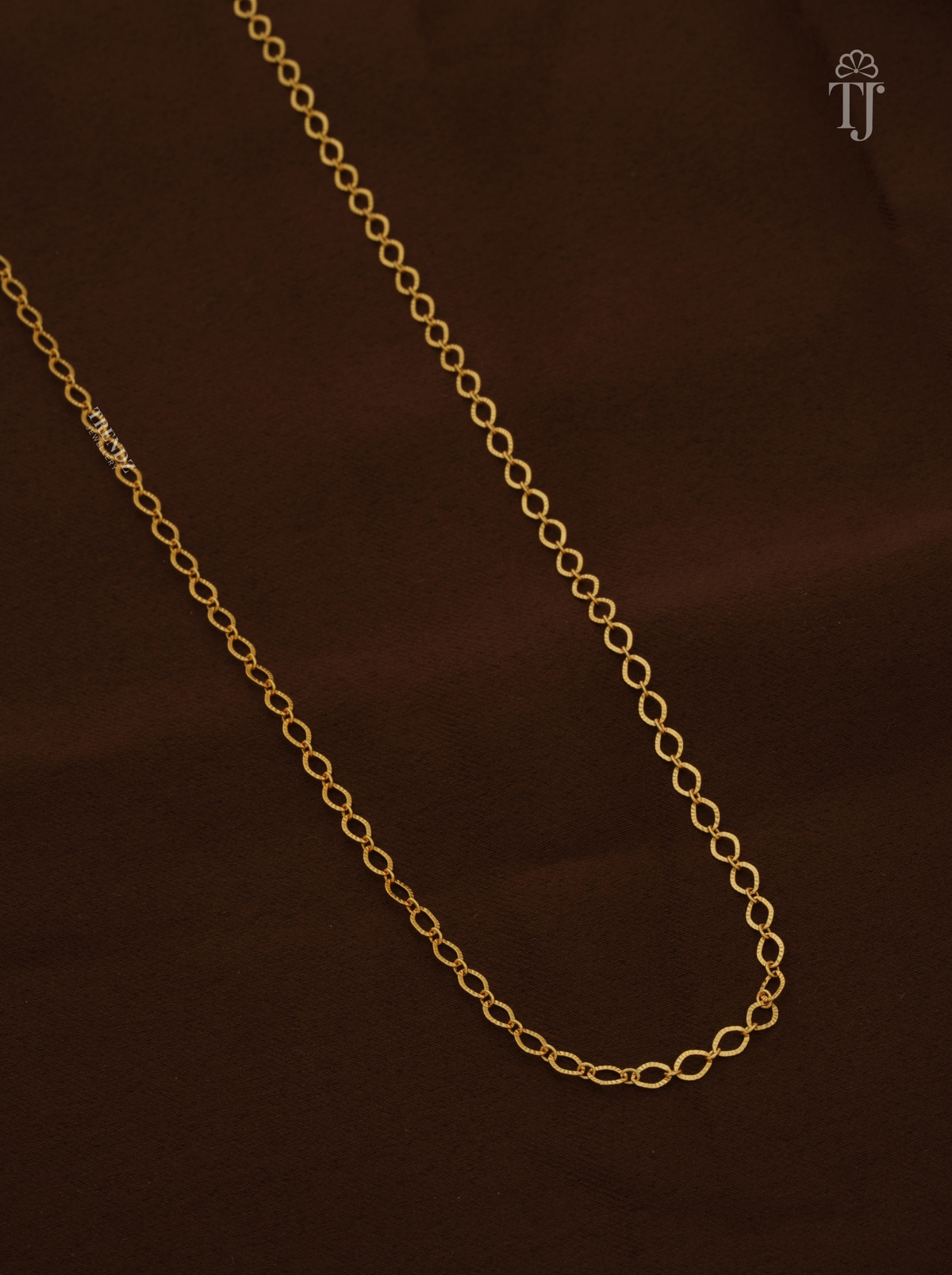 Close view of thin gold plated oval link chain with textured links
