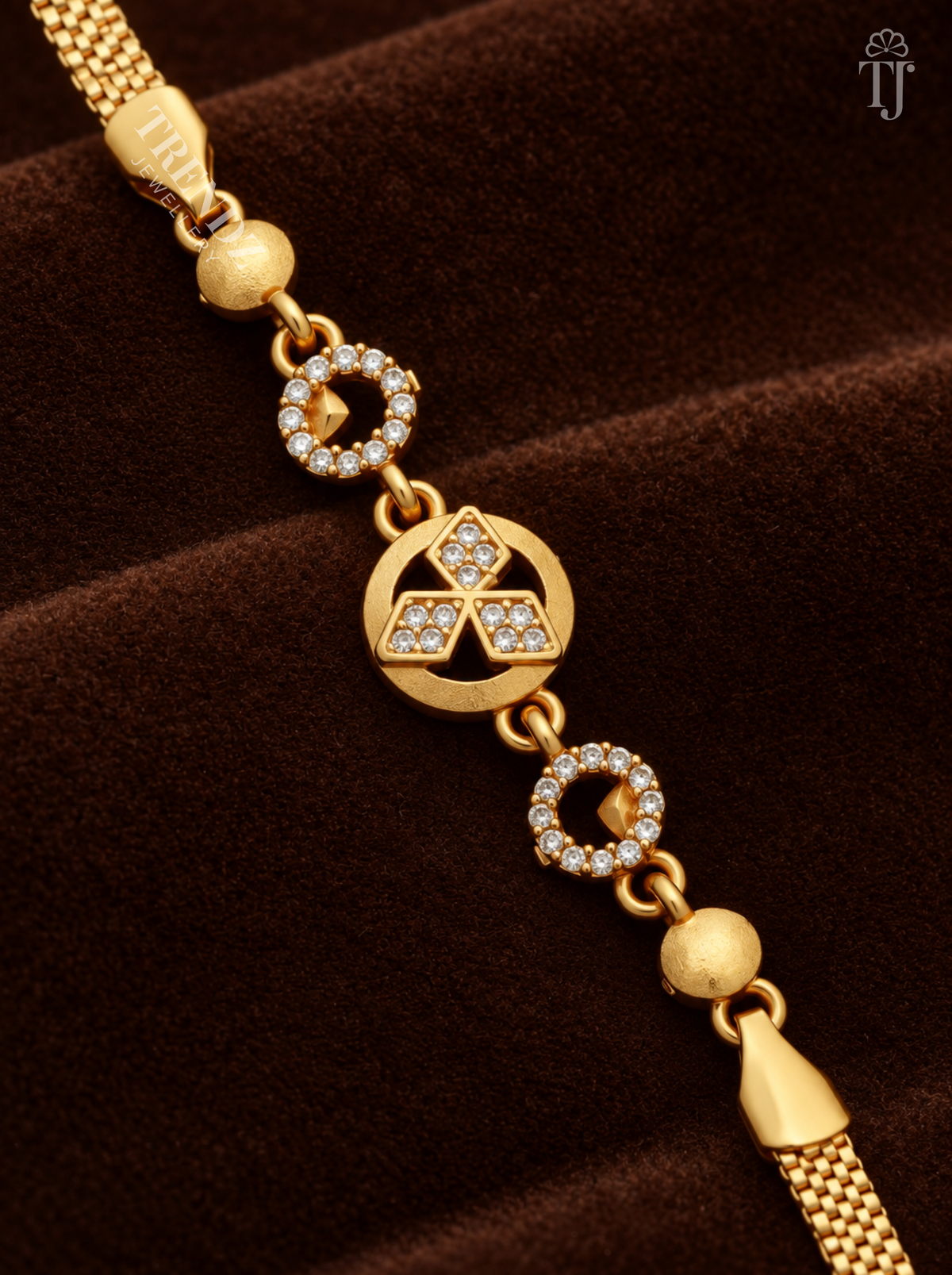 Close-up of round gold charm with three AD stone diamond shapes and stone rings