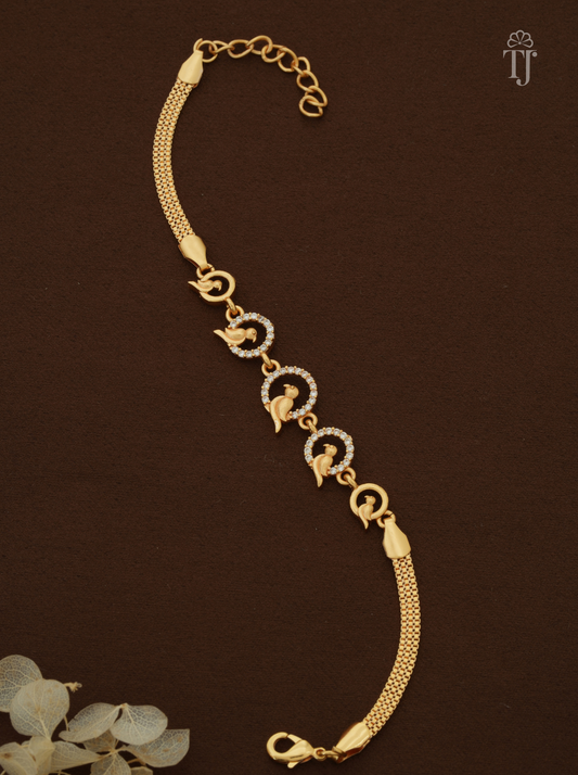 A gold-plated chain bracelet with three circular motifs set with small clear stones and three peacock charms, displayed on a dark brown background.