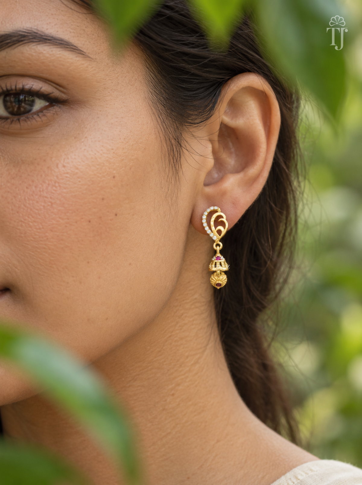 Side view of woman wearing gold plated AD stone jhumka drop earrings