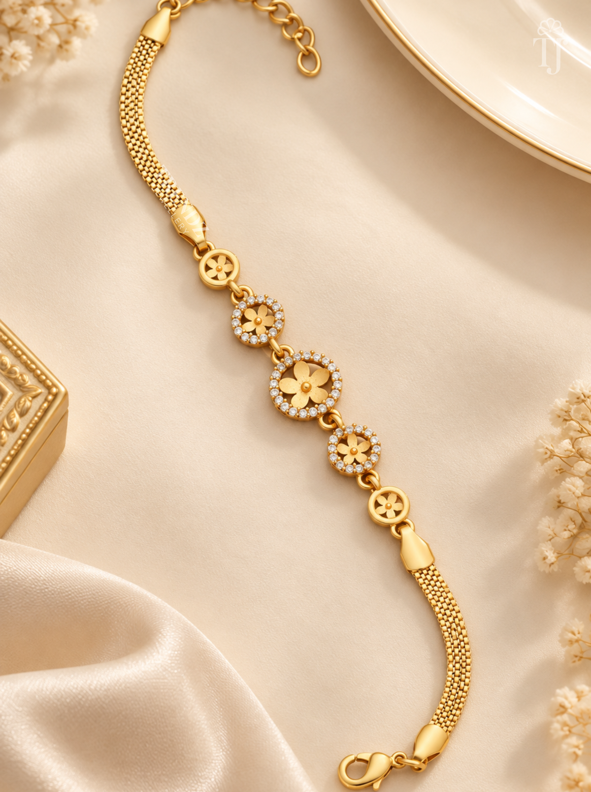 Adjustable gold plated flower bracelet with lobster clasp and extender chain on cream satin