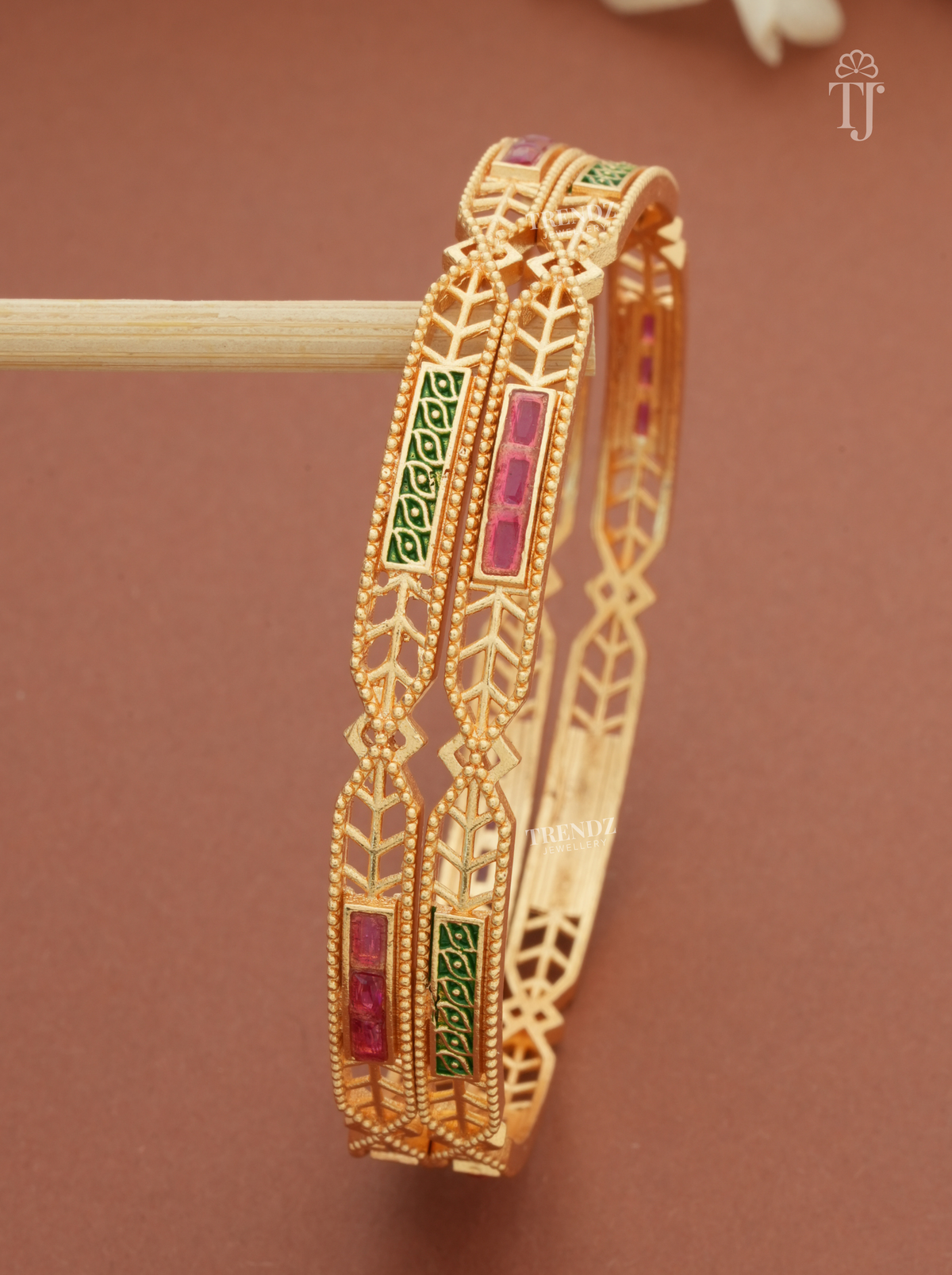 Close-up of pink stones and green meena work on gold plated bangles
