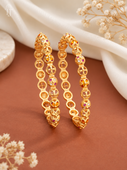 Orange pink stone beaded artificial bangles for women, gold plated brass, pair on warm backdrop


