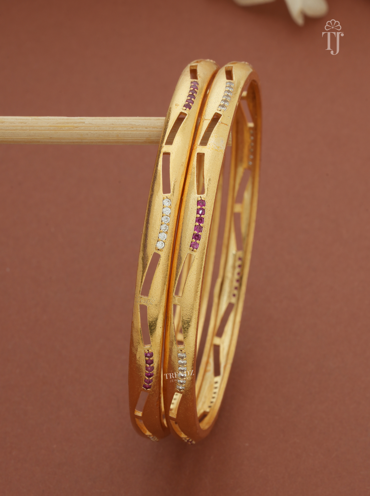 Close-up of pink and white stone lines on glossy gold plated bangles