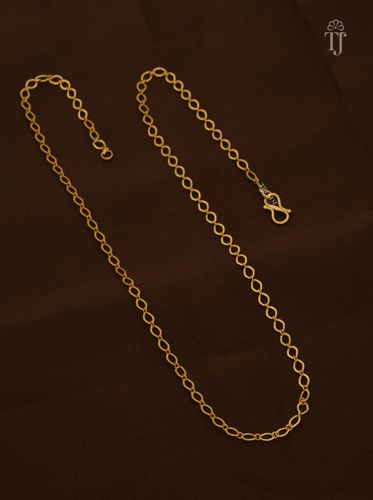 Artificial gold chain for ladies with oval links and S-hook on brown fabric