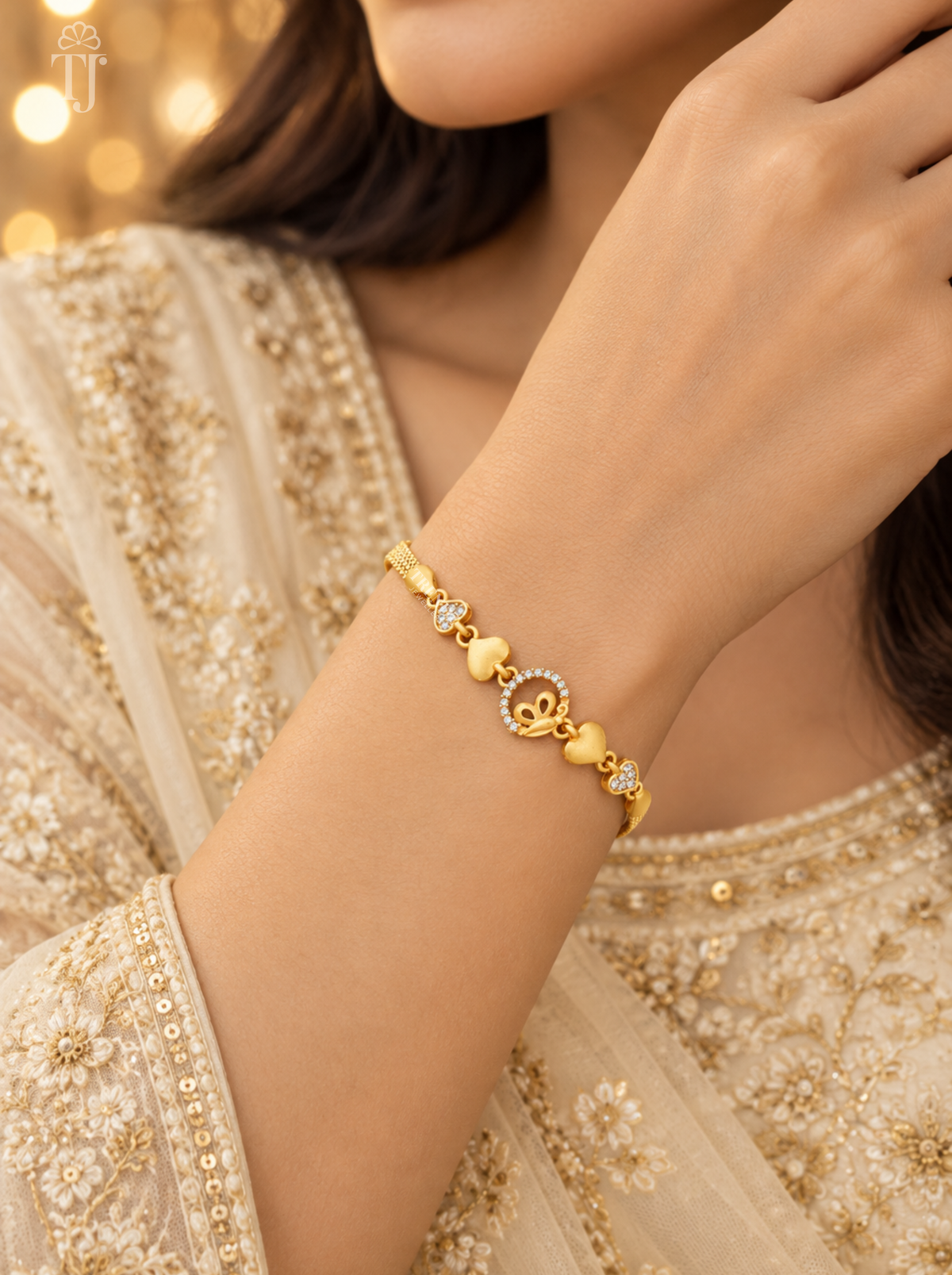 Woman in beige embroidered outfit wearing gold plated butterfly heart bracelet on her wrist
