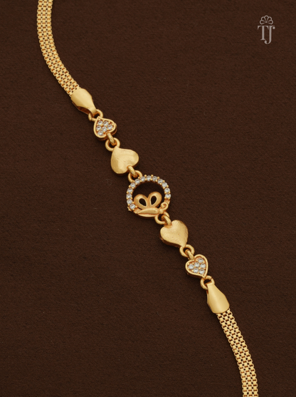 A gold heart-link chain bracelet with a central heart-and-crown motif set with small clear stones, displayed on a dark brown textured background.