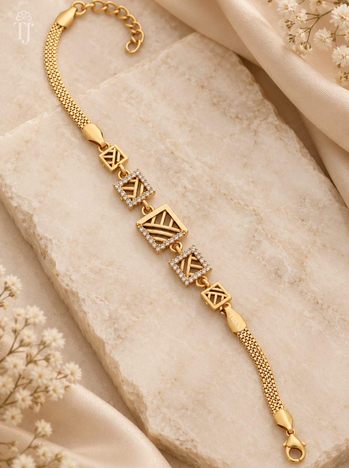 Cubic zirconia bracelet, gold plated with five square openwork charms on cream marble