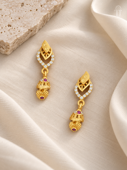 Pair of gold plated double leaf earrings with pink stone jhumka on cream linen