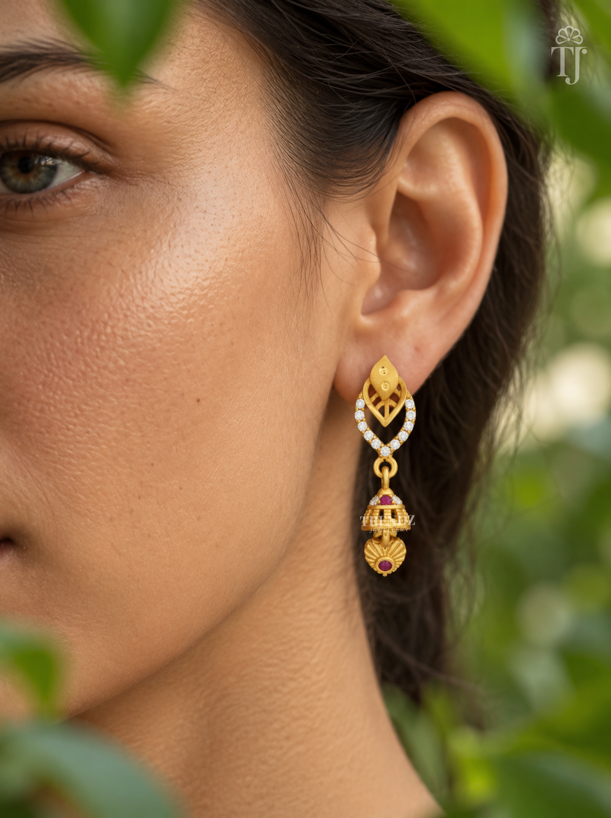 Side view of woman wearing gold plated double leaf jhumka drop earrings