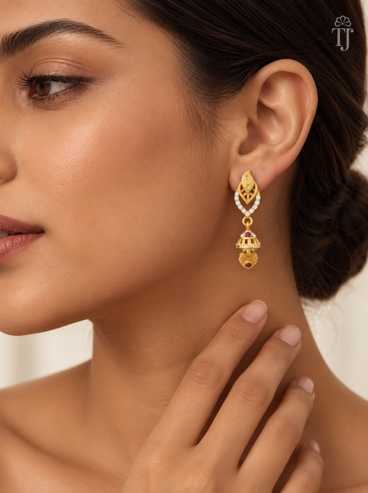 Woman wearing small gold plated double leaf jhumka earrings with AD stones