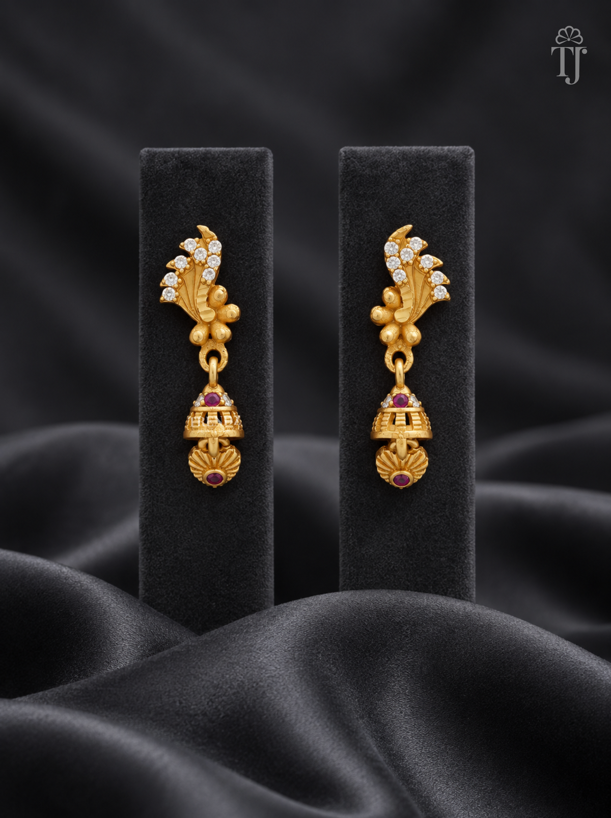 Gold plated feather design jhumka earrings with AD stones on black display stand