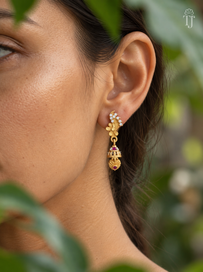 Side view of woman wearing gold plated feather design jhumka drop earrings