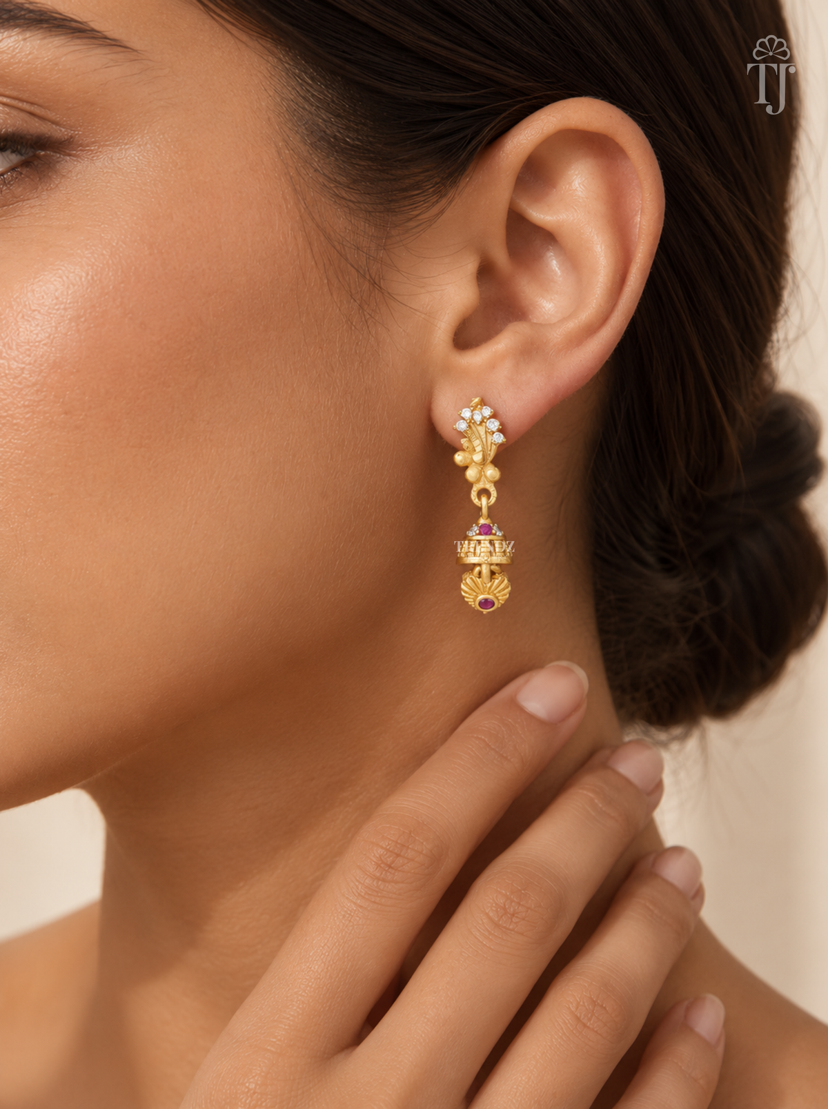 Woman wearing small gold plated feather design jhumka earrings with AD stones