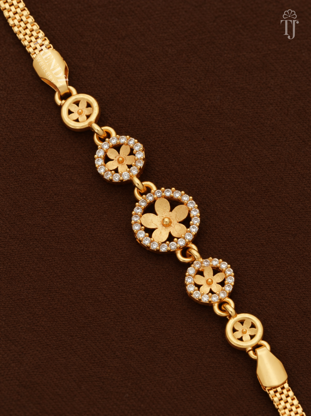 Flower bracelet for women, close-up of gold flower charms in white AD stone rings on brown velvet