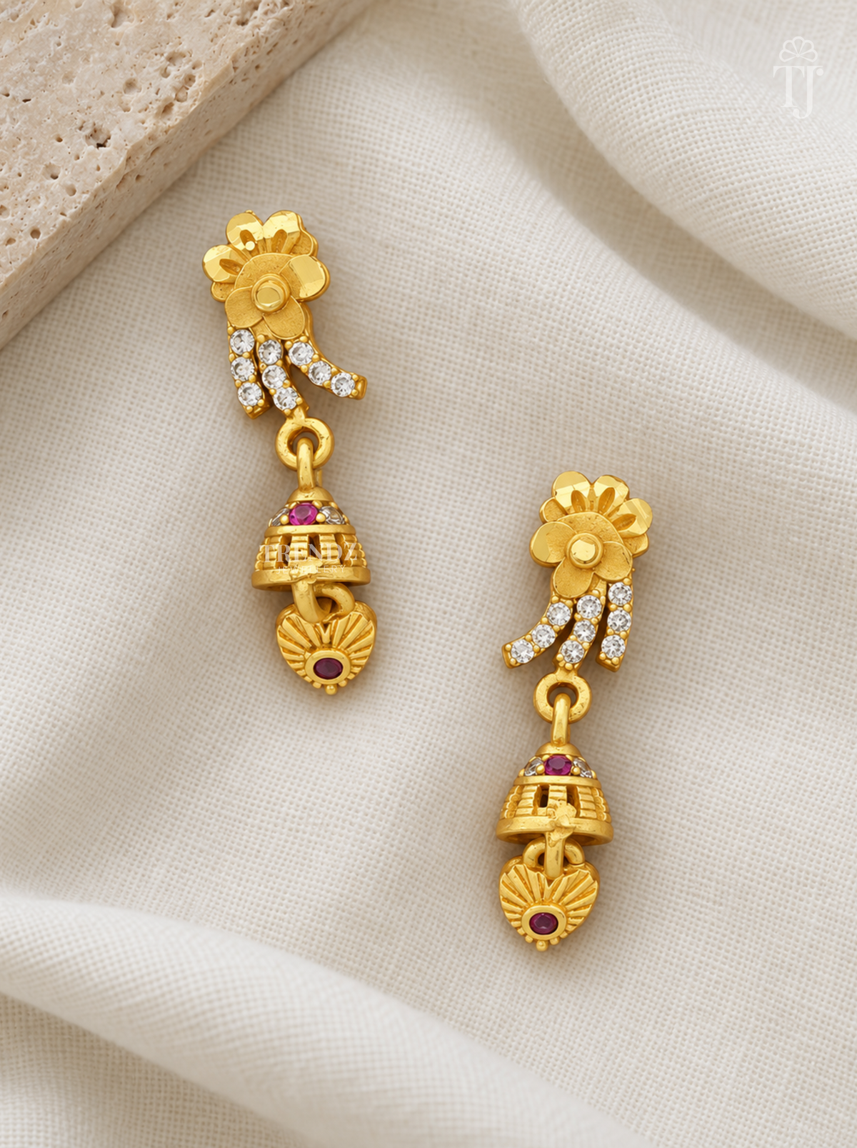 Pair of gold plated flower drop earrings with pink stone jhumka on cream linen