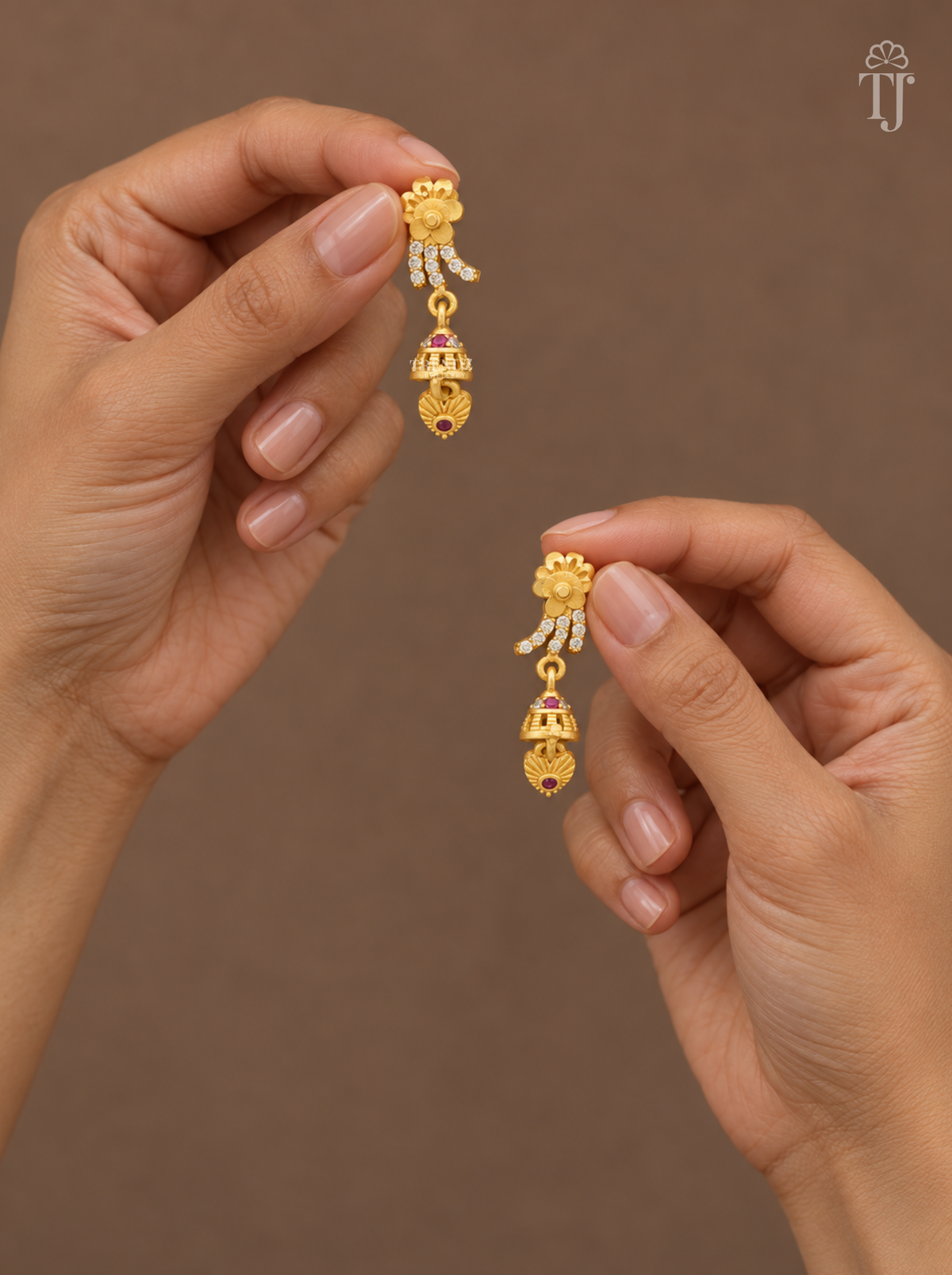 Fingers holding gold plated flower drop earrings with mini jhumka