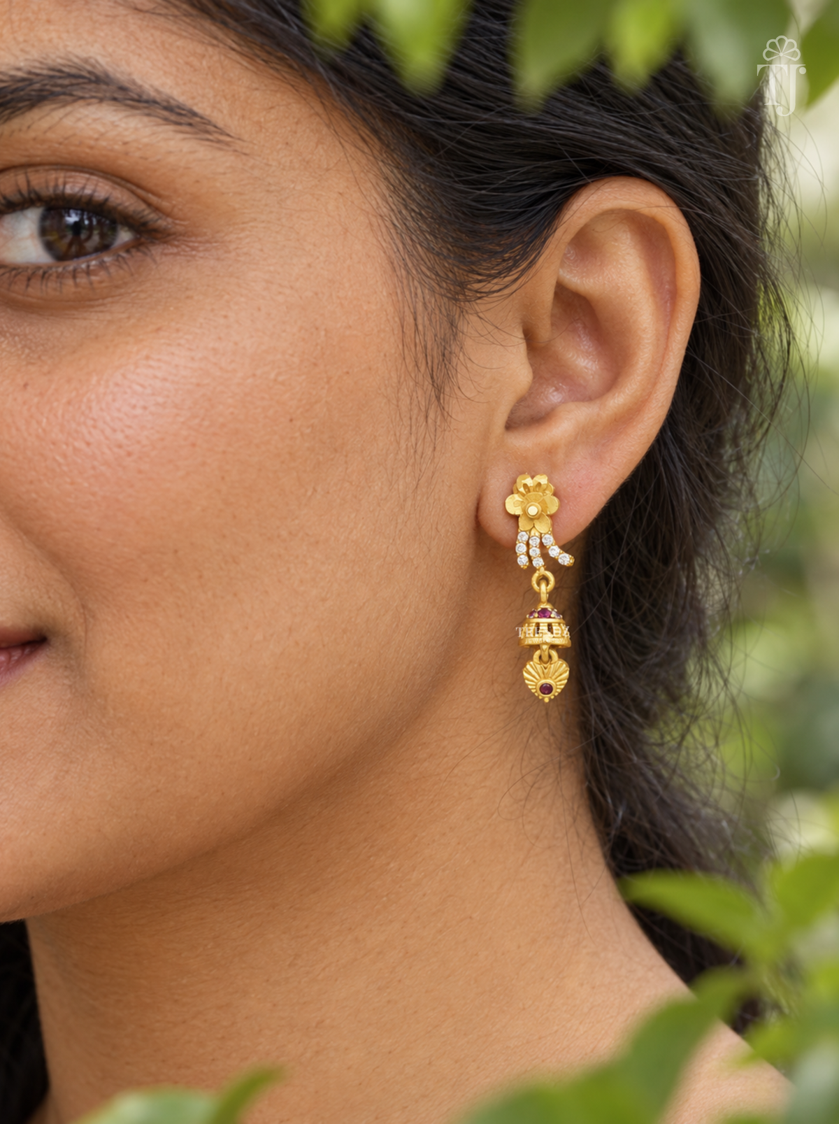 Side view of woman wearing gold plated flower jhumka drop earrings