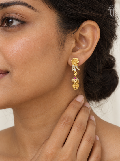 Woman wearing small gold plated flower drop earrings with AD stone lines