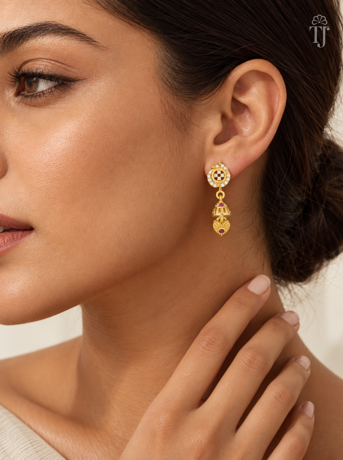 Woman wearing small gold plated stone flower jhumka earrings