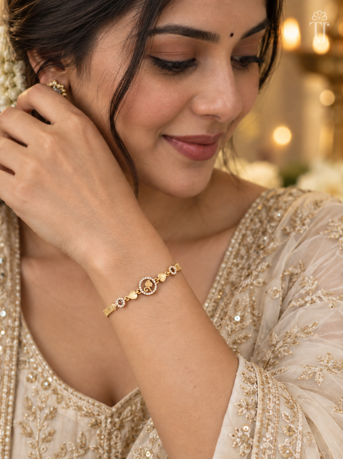 Woman in beige embroidered outfit wearing gold plated leaf charm bracelet on her wrist