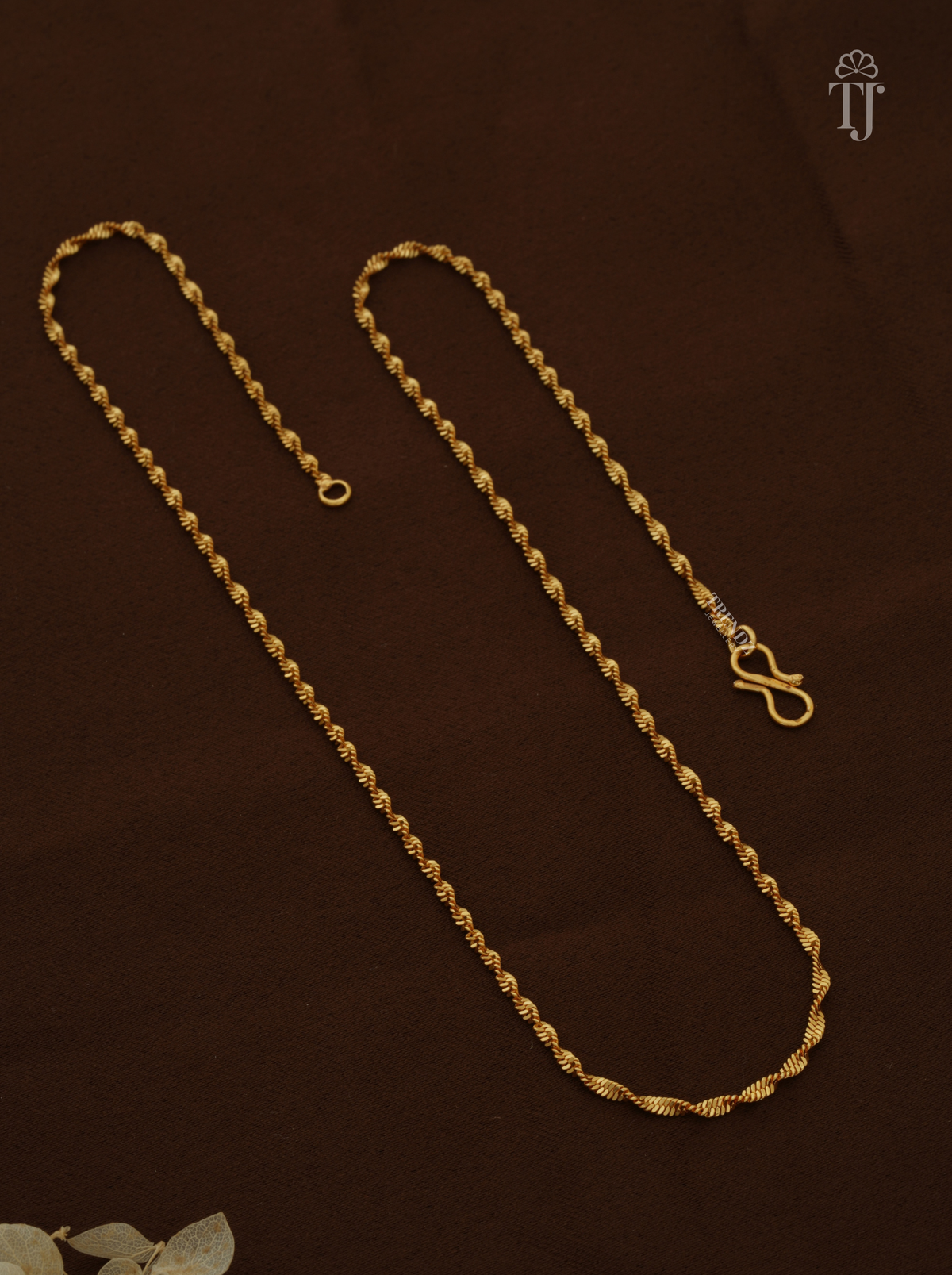 Gold plated chain with twisted design and S-hook on brown fabric