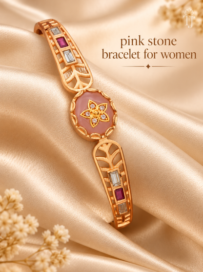 A gold-plated bracelet with pink stone accents and clear and purple gemstones, displayed on a beige satin fabric background with decorative dried flowers and text reading 'pink stone bracelet for women'.