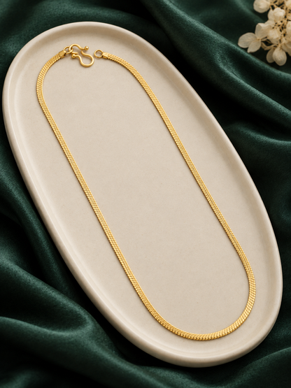 Thin gold plated snake chain laid on cream oval tray with green velvet