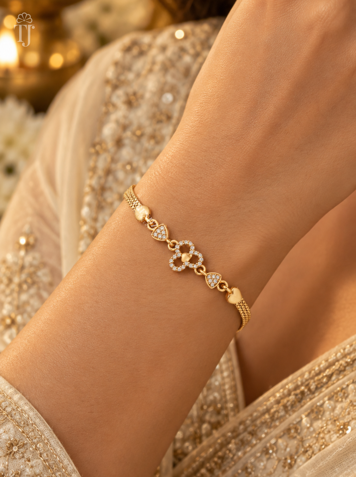 Gold plated heart flower bracelet worn on wrist with beige embroidered outfit