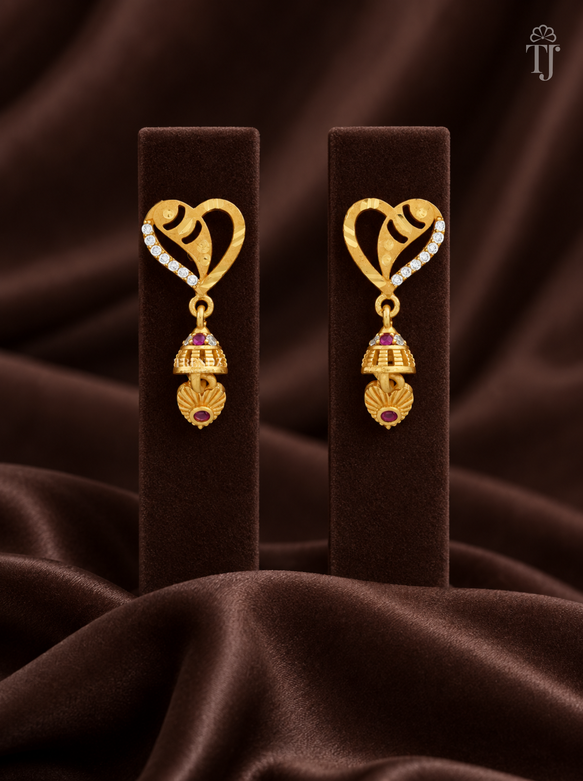 Gold plated heart jhumka earrings with AD stones on brown velvet display stand