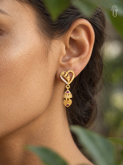 Side view of woman wearing gold plated heart jhumka drop earrings