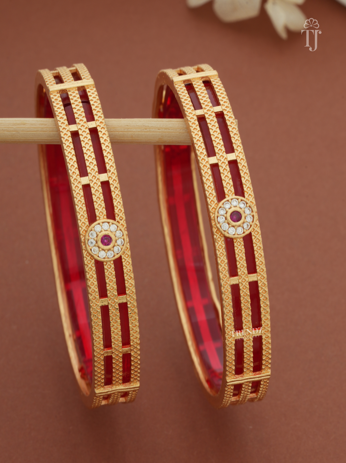 Close-up of floral medallion with white and pink stones on gold-plated bangles
