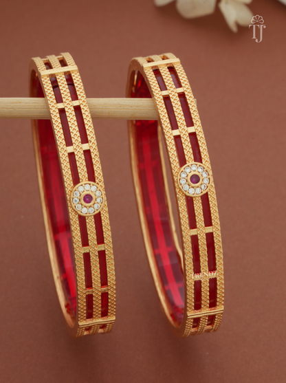 Close-up of floral medallion with white and pink stones on gold-plated bangles