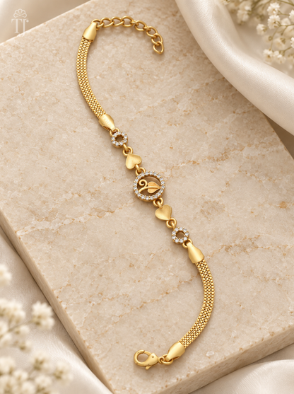 Gold plated leaf charm bracelet laid on cream stone with white fabric