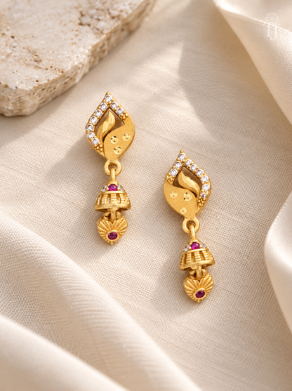 Pair of gold plated leaf design earrings with heart-shaped drop on cream linen