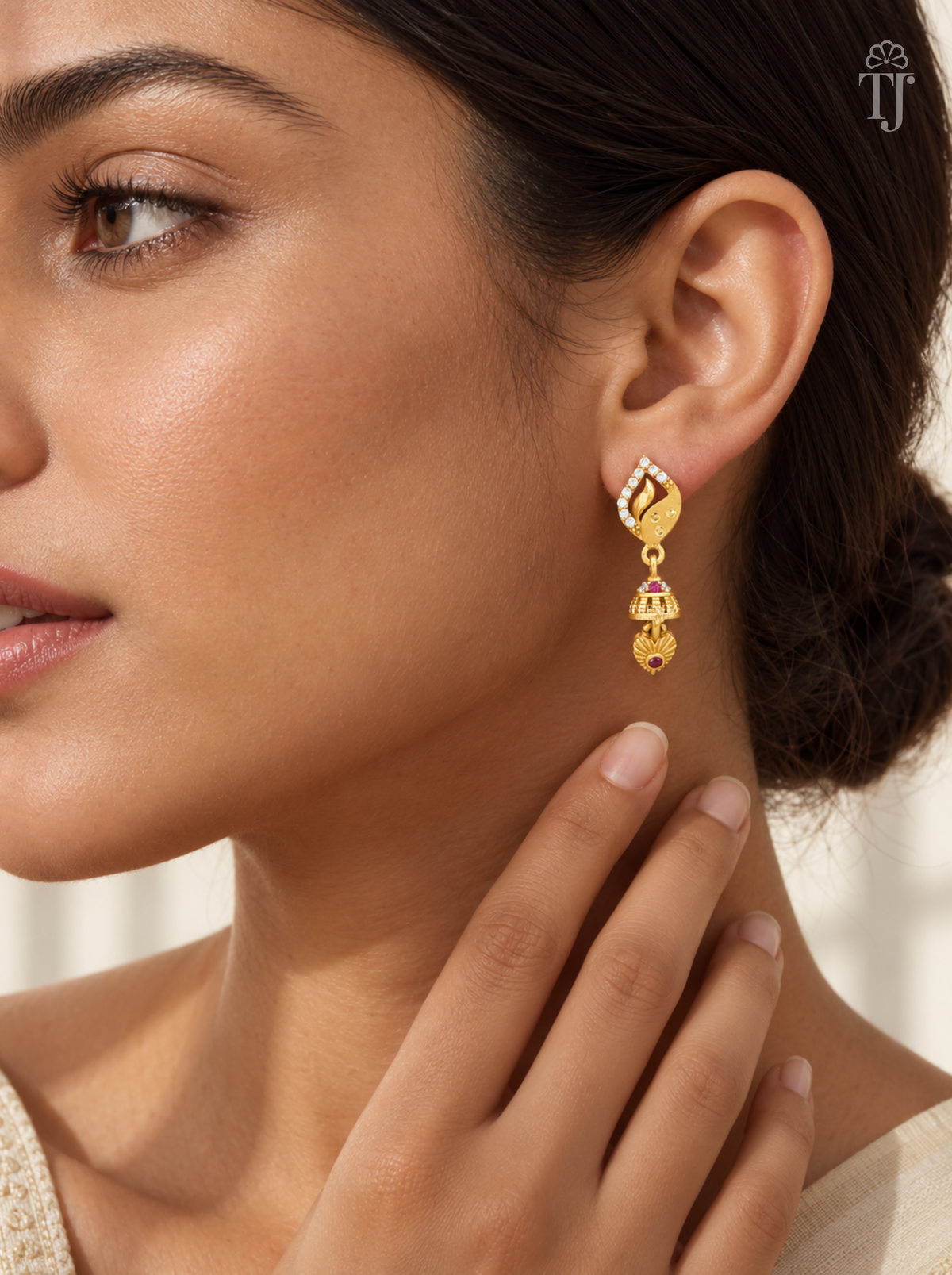 Woman wearing small gold plated leaf design jhumka earrings with AD stones