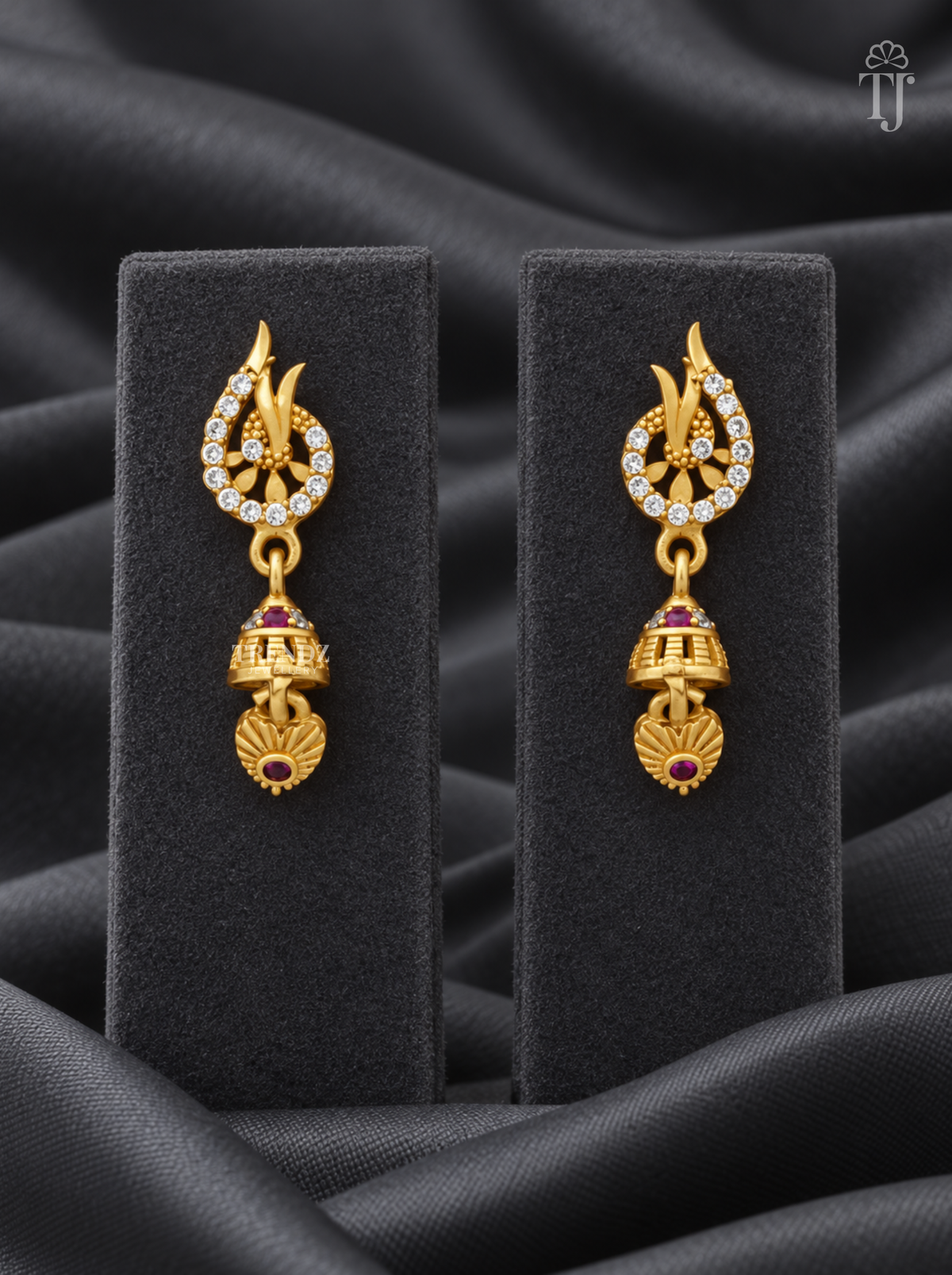 Gold plated leaf tip jhumka earrings with AD stones on black display stand