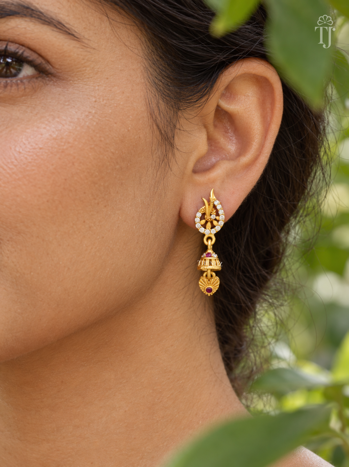 Side view of woman wearing gold plated leaf design jhumka earrings