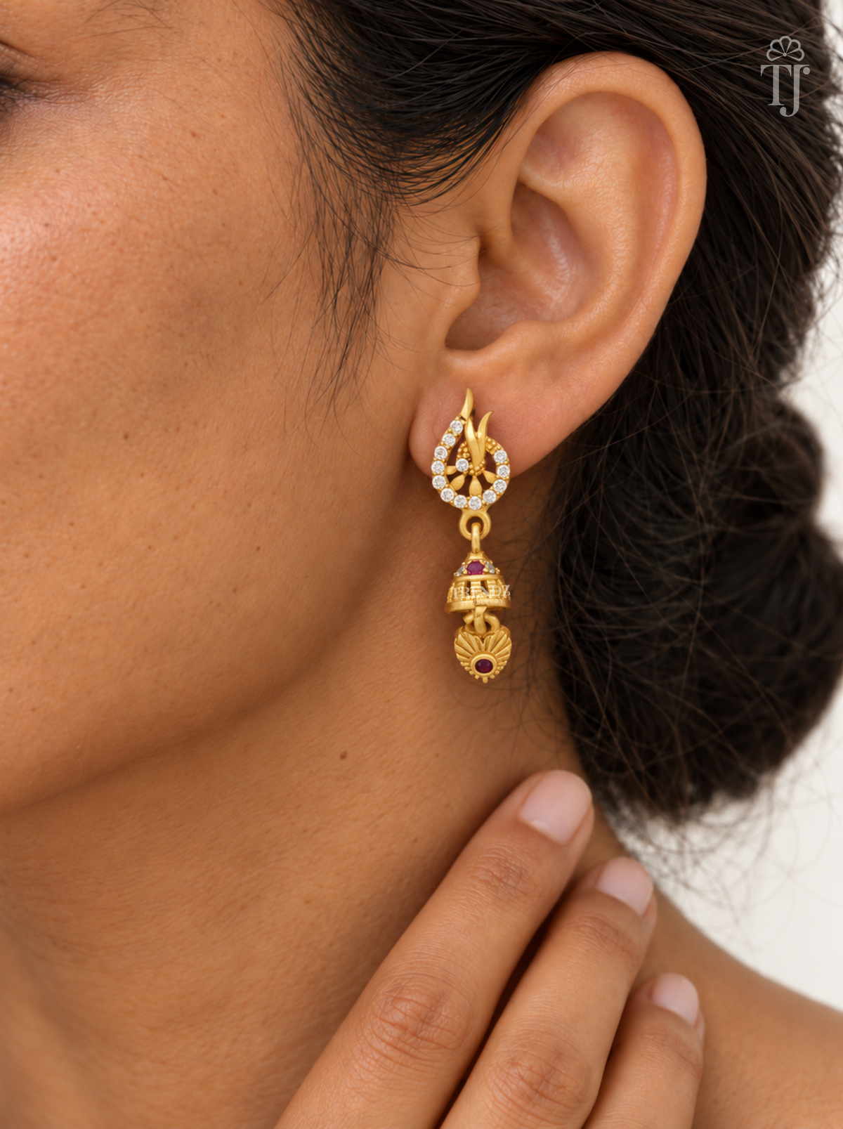 Woman wearing gold plated leaf tip jhumka earrings with AD stone ring