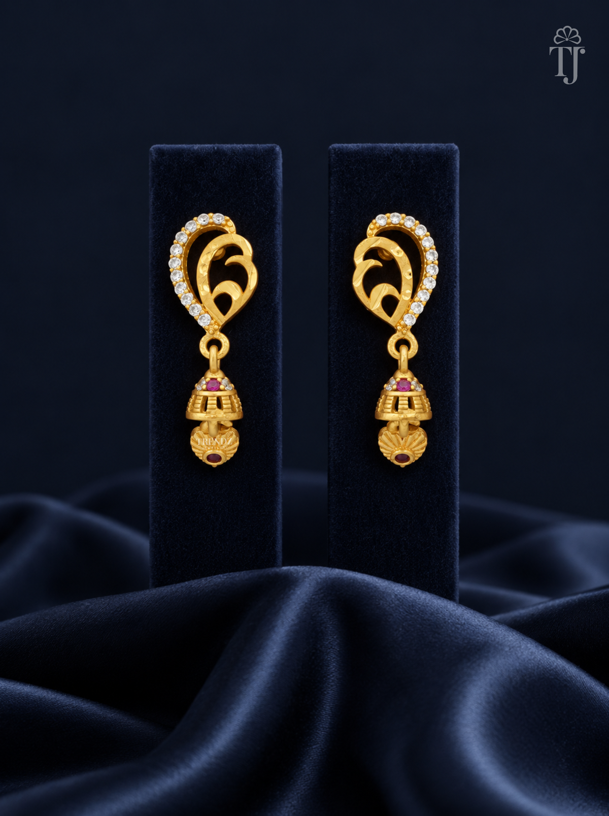Gold plated mango design jhumka earrings with AD stones on navy display stand