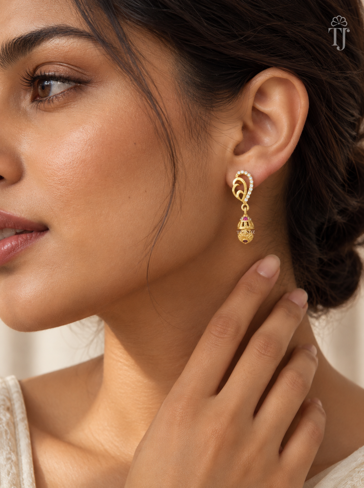 Woman wearing small gold plated mango design jhumka earrings with AD stones