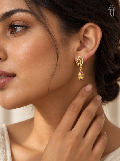 Woman wearing small gold plated mango design jhumka earrings with AD stones