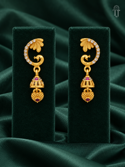 Gold plated peacock jhumka earrings with AD stones on dark green velvet display stand