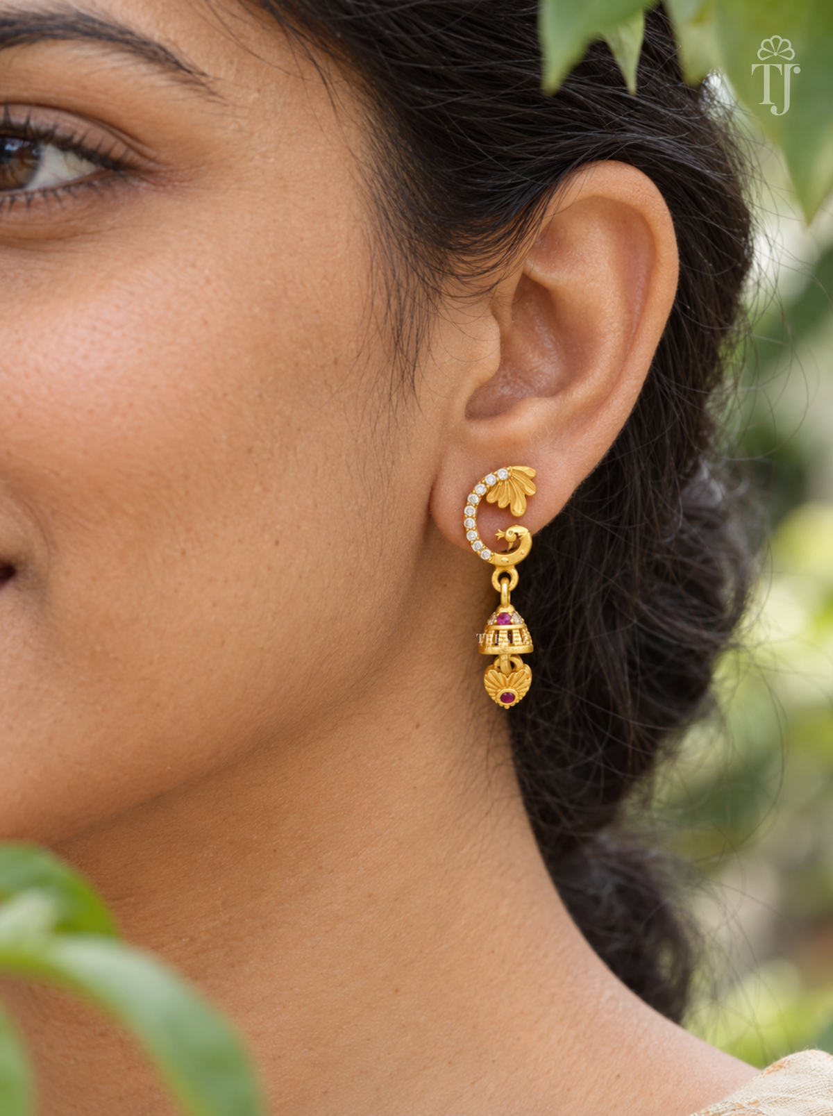 Side view of woman wearing gold plated peacock bell drop earrings