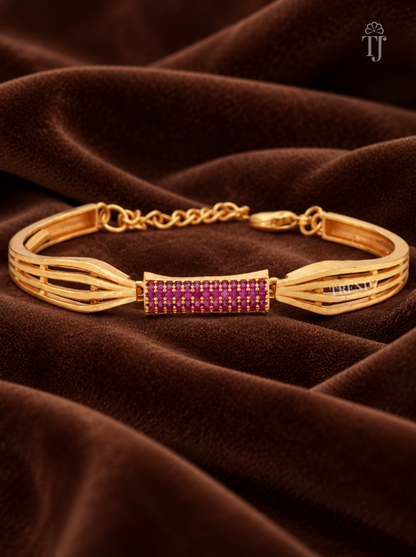 A gold-plated cuff bracelet with a central rectangular bar set with rows of small magenta-purple stones, displayed on draped brown velvet fabric.