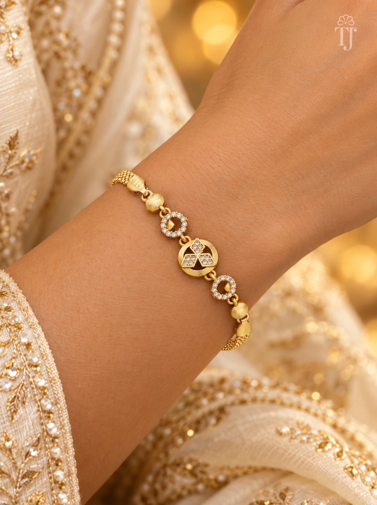 Woman in cream embroidered dress wearing gold plated round charm bracelet