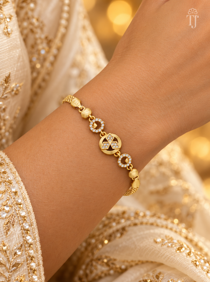 Woman in cream embroidered dress wearing gold plated round charm bracelet