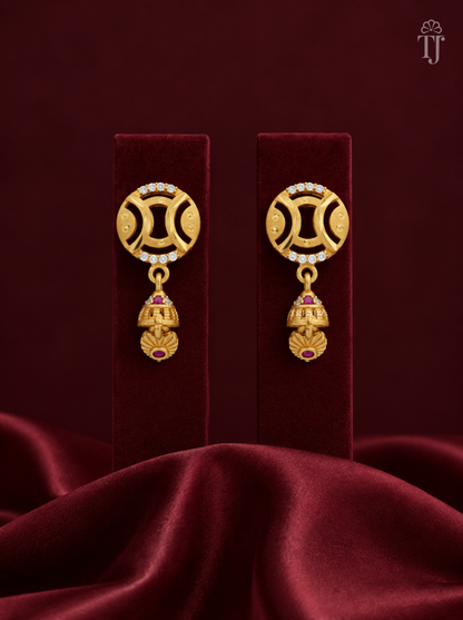 Gold plated round jhumka earrings with AD stones on maroon velvet display stand