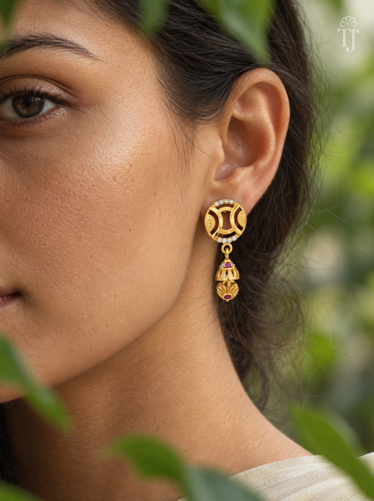 Side view of woman wearing gold plated round jhumka drop earrings