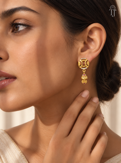 Woman wearing small gold plated round jhumka earrings with AD stones